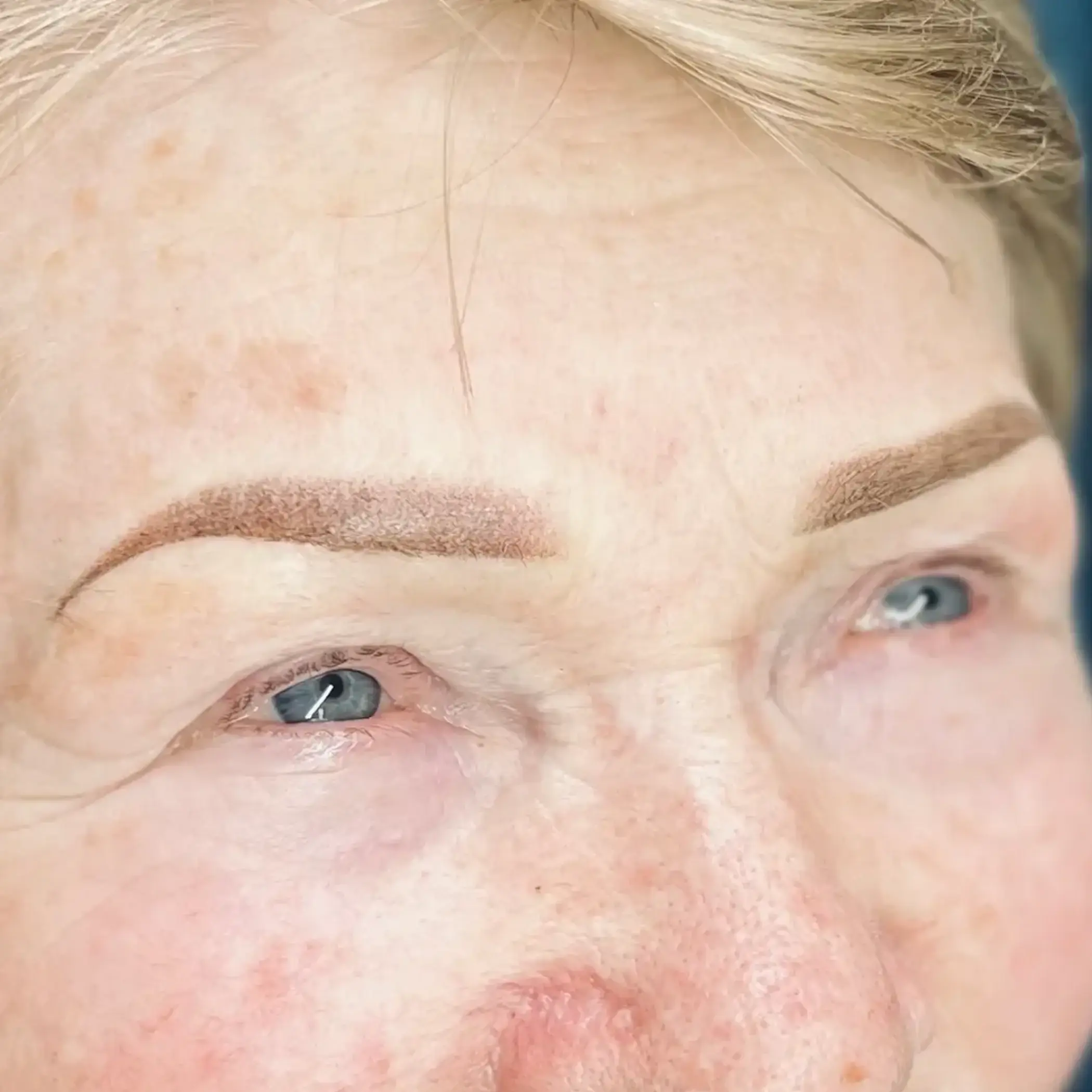 artist shaping eyebrow stencil on client