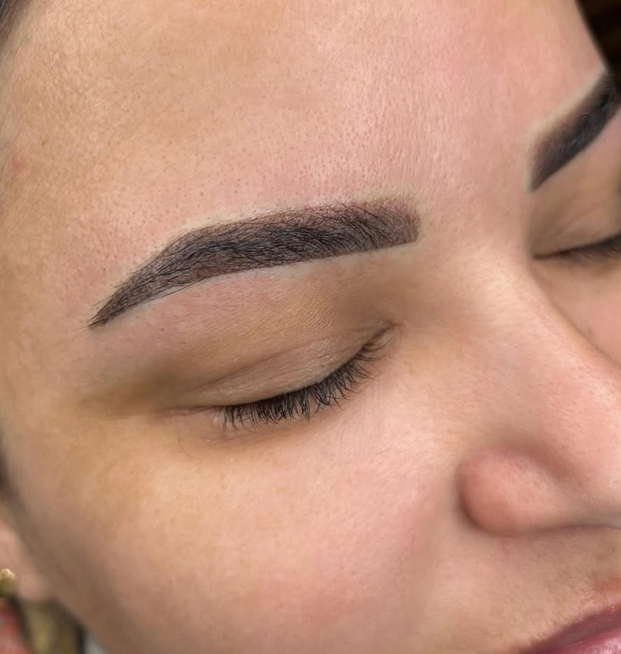 artist shaping eyebrow stencil on client